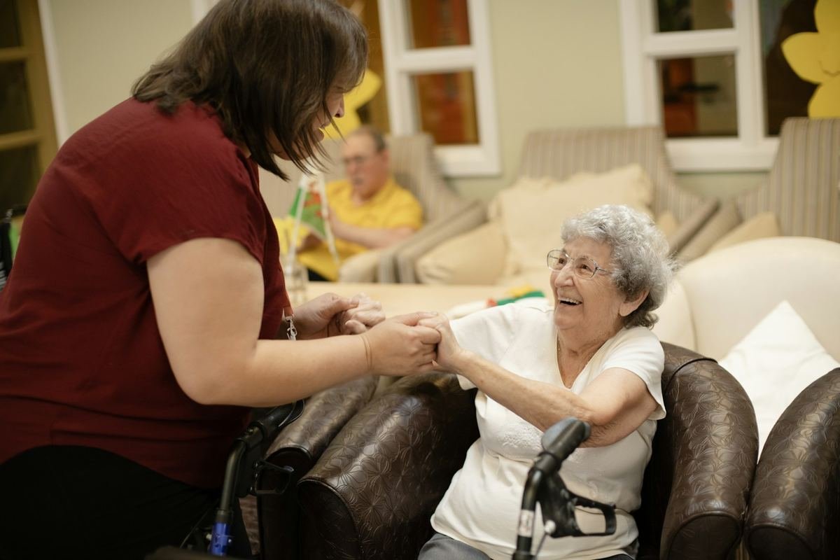 Caregiver helping a smiling older woman with her walker