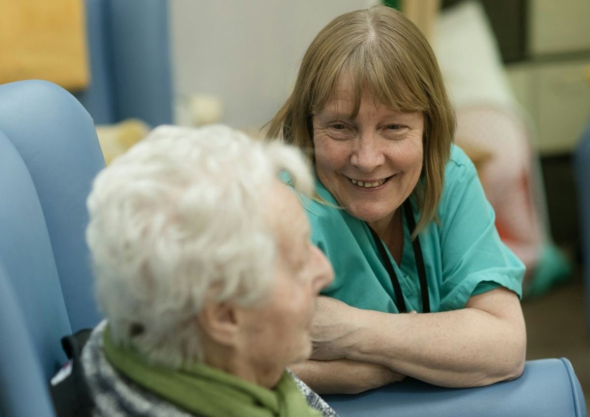 Nurse in scrubs smiling with an older woman