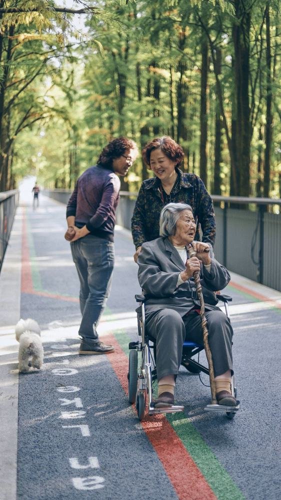 Smiling older woman with a cane, seated outdoors with family